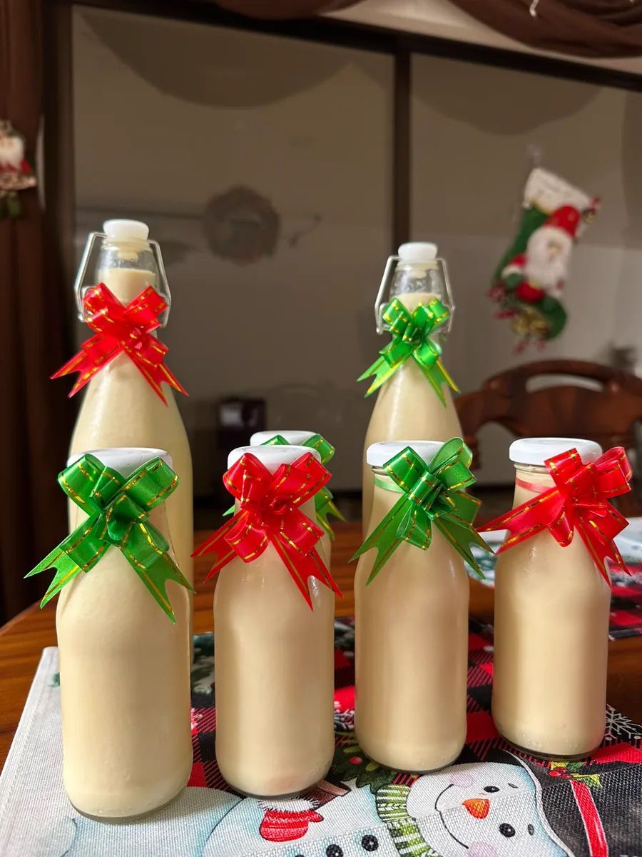 Botellas de rompope con moñas rojas y verdes junto a una bota navideña