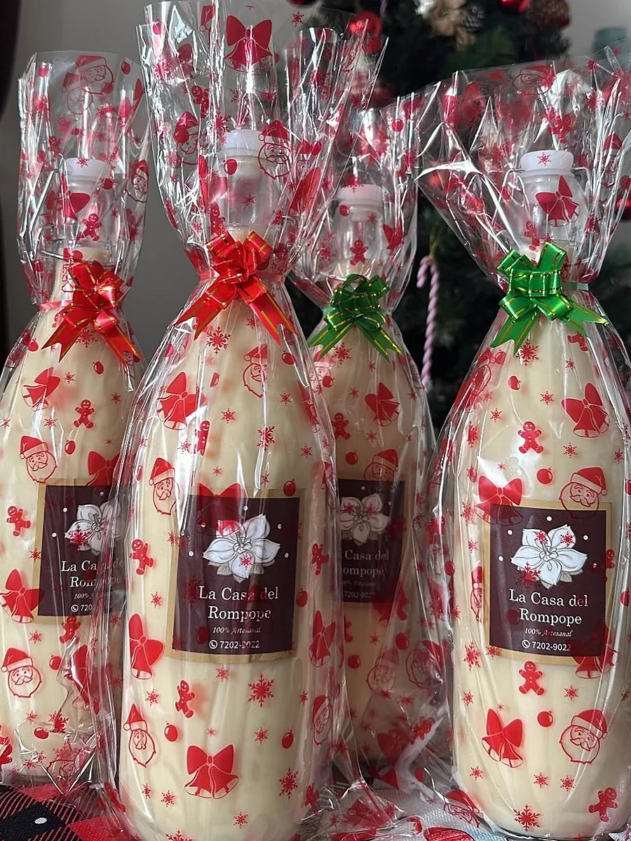 Botellas de rompope envueltas en celofán navideño con moñas rojas y verdes